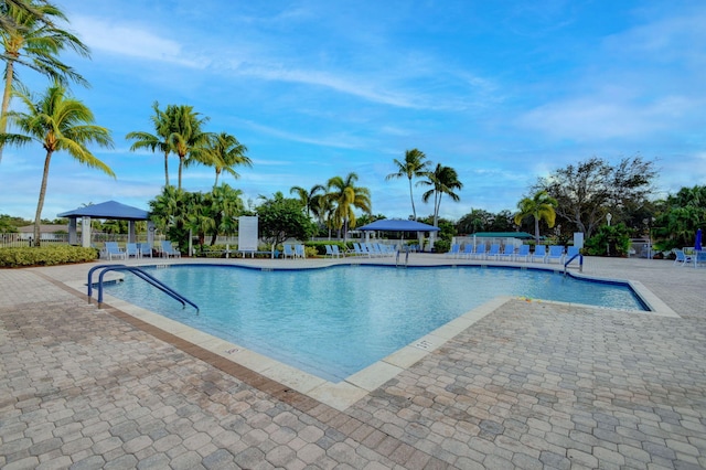 community pool with a patio area, a gazebo, and fence
