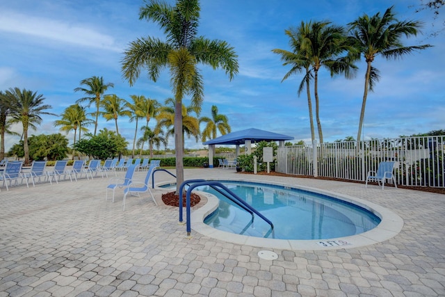 community pool with a gazebo, fence, and a patio