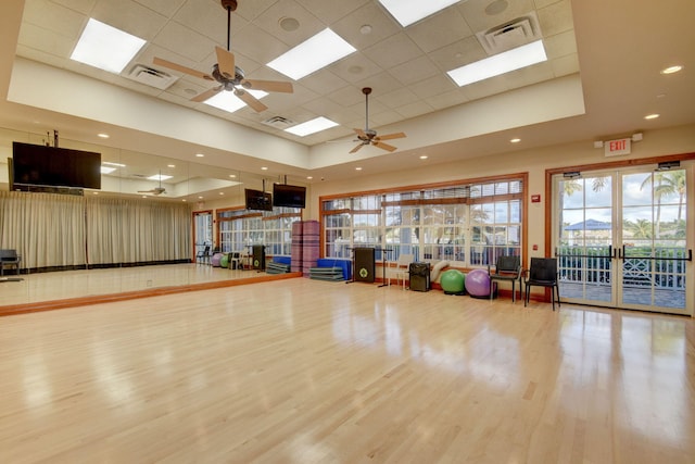 exercise area featuring a paneled ceiling, wood finished floors, ceiling fan, and visible vents