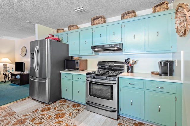 267 Old Country Rd S, Wellington, FL 33414 - kitchen featuring a textured ceiling, blue cabinetry, under cabinet range hood, light countertops, and stainless steel appliances