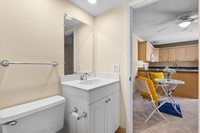 bathroom with a ceiling fan, toilet, vanity, and a textured ceiling