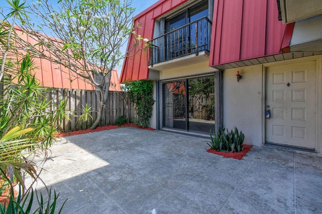 view of patio with fence and a balcony