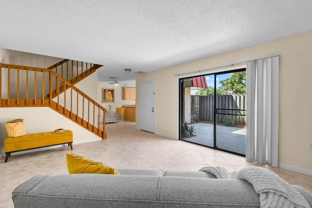 tiled living area with stairs, a textured ceiling, a ceiling fan, and baseboards