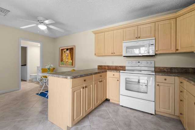 kitchen featuring white appliances, light brown cabinetry, a peninsula, dark countertops, and light tile patterned floors