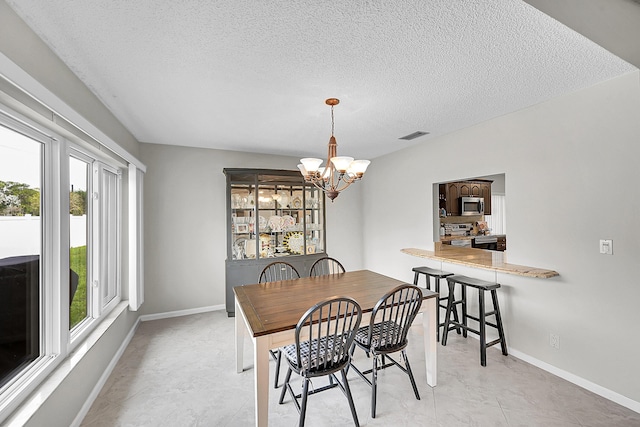 dining area featuring visible vents, baseboards, a notable chandelier, and a textured ceiling