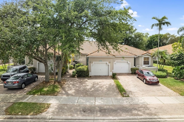 view of front of house featuring a tile roof, decorative driveway, an attached garage, and stucco siding