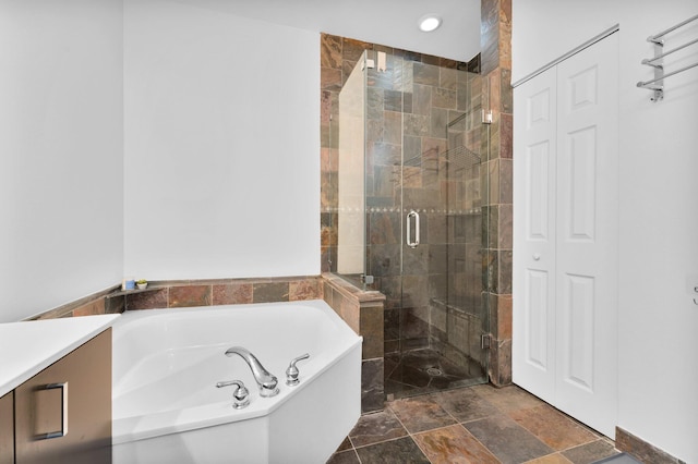 full bath with a stall shower, vanity, and a bath