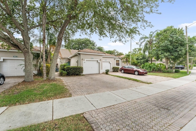 view of front of home with a tile roof, decorative driveway, stucco siding, and an attached garage