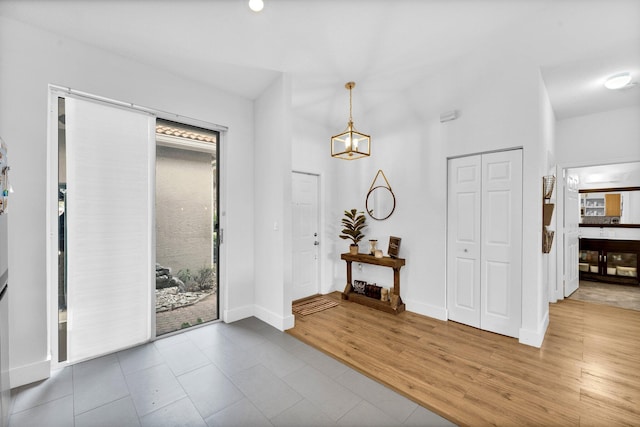foyer entrance with a healthy amount of sunlight, a notable chandelier, baseboards, and wood finished floors