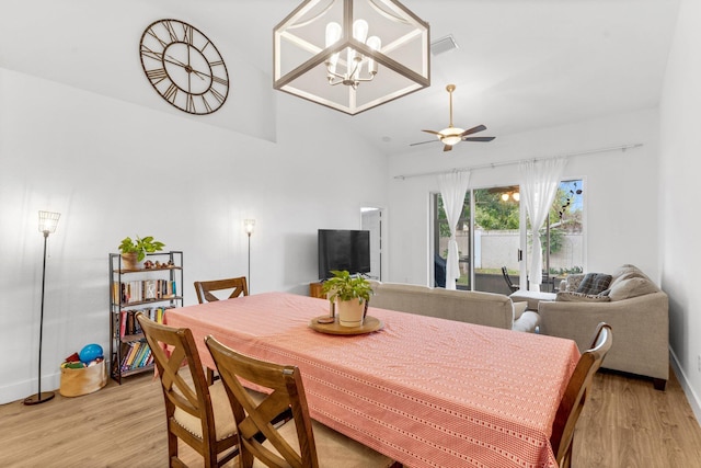 dining room featuring light wood finished floors, vaulted ceiling, visible vents, and a ceiling fan
