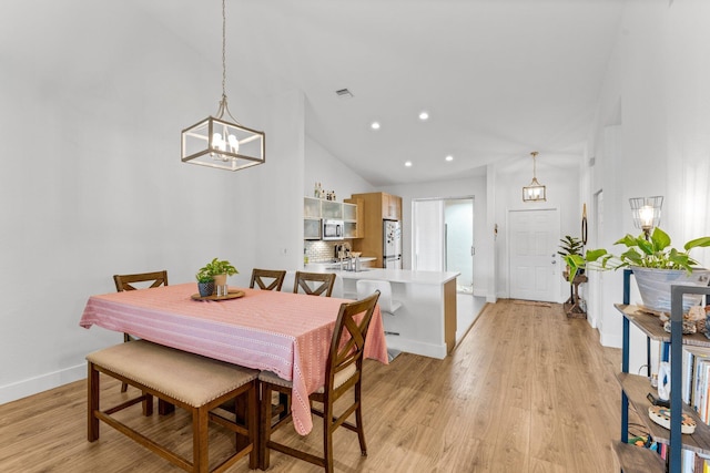dining space with an inviting chandelier, baseboards, light wood-style floors, and visible vents