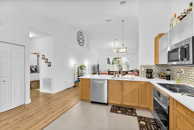 kitchen featuring light countertops, a sink, a peninsula, stainless steel appliances, and visible vents