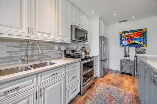1199 Hillsboro Mile Unit 119, Hillsboro Beach, FL 33062 - kitchen featuring appliances with stainless steel finishes, a sink, white cabinetry, tasteful backsplash, and visible vents