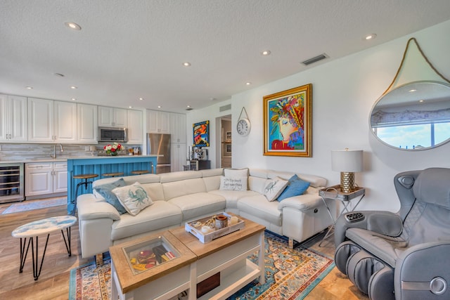 1199 Hillsboro Mile Unit 119, Hillsboro Beach, FL 33062 - living area with visible vents, a textured ceiling, wine cooler, and light wood finished floors