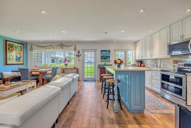 1199 Hillsboro Mile Unit 119, Hillsboro Beach, FL 33062 - kitchen with a kitchen bar, a center island, light wood-style floors, stainless steel appliances, and white cabinetry