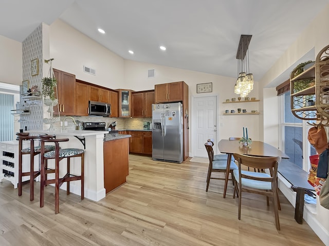 kitchen with a peninsula, visible vents, brown cabinets, decorative backsplash, and stainless steel appliances