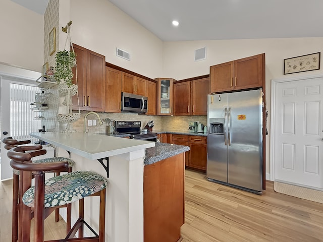 kitchen with brown cabinets, visible vents, a peninsula, and stainless steel appliances