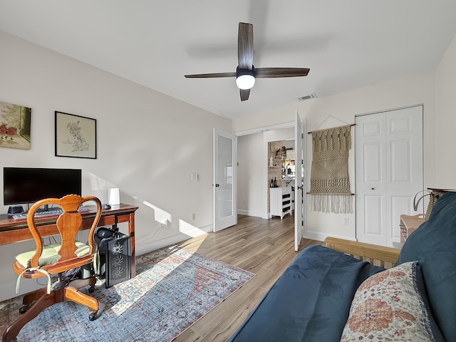 bedroom with baseboards, visible vents, multiple closets, ceiling fan, and wood finished floors