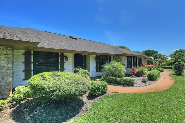 1090 31st Ave, Vero Beach, FL 32960 - exterior space featuring stone siding, a shingled roof, and a front lawn