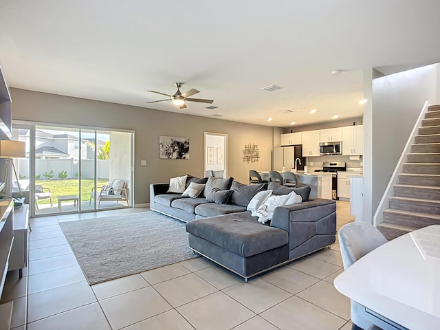 living room with light tile patterned flooring, stairway, visible vents, and ceiling fan