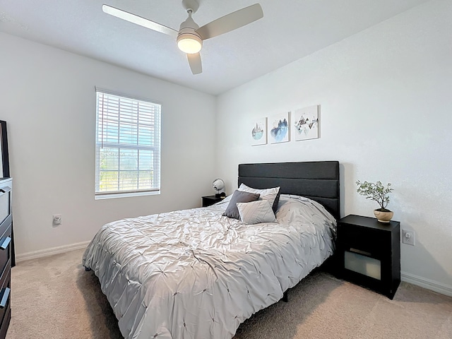 bedroom featuring light carpet, a ceiling fan, and baseboards