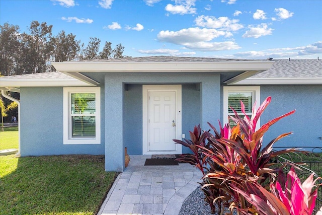 1200 Hartman Rd, Fort Pierce, FL 34947 - view of exterior entry with stucco siding, a lawn, and roof with shingles