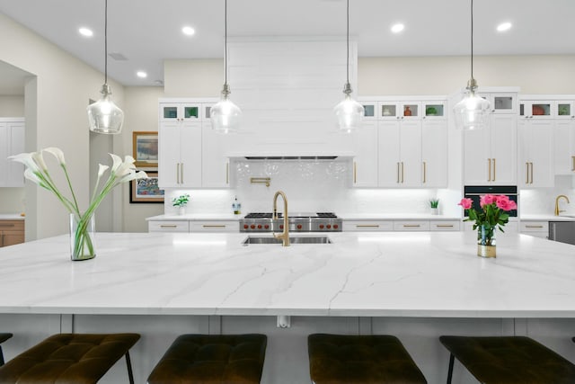kitchen with a spacious island, oven, decorative backsplash, and a sink
