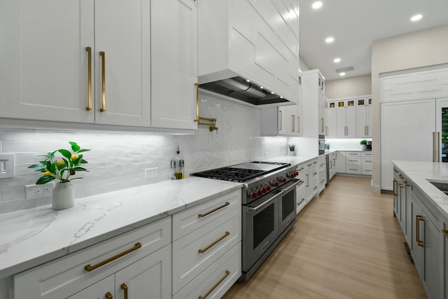 kitchen with white cabinets, custom range hood, backsplash, and range with two ovens