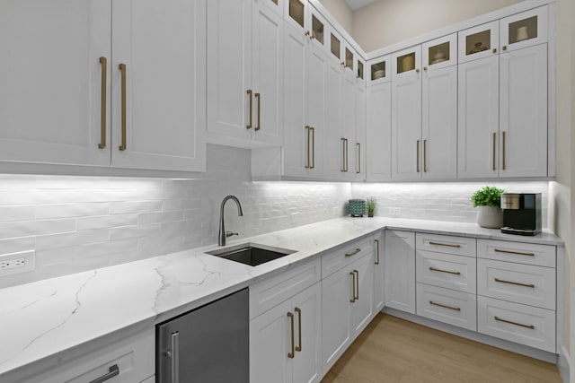 kitchen featuring white cabinetry, tasteful backsplash, a sink, and glass insert cabinets