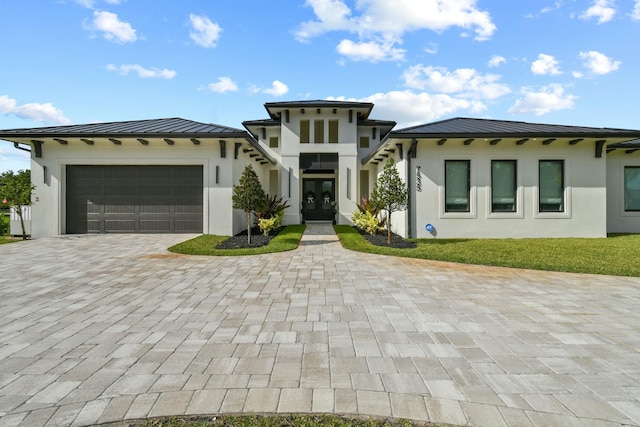 prairie-style house featuring stucco siding, an attached garage, a standing seam roof, french doors, and decorative driveway