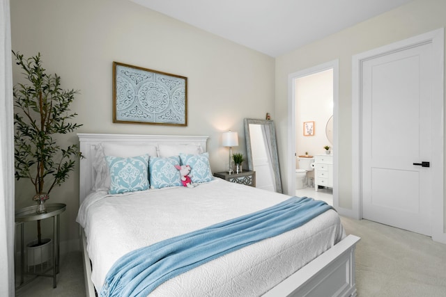 bedroom with ensuite bath and light colored carpet