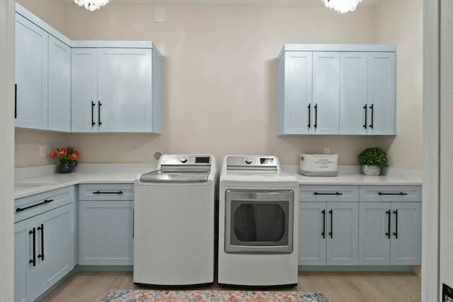 laundry room featuring washing machine and dryer, cabinet space, and light wood finished floors