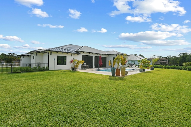 rear view of house with a fenced in pool, a patio area, a standing seam roof, a lawn, and metal roof