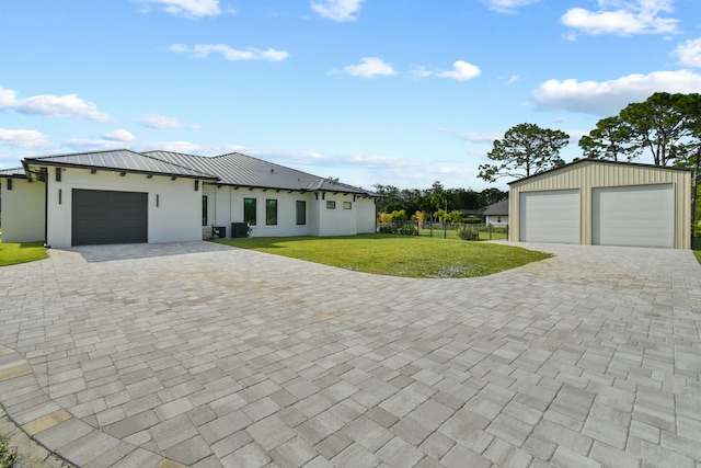 single story home with a detached garage, metal roof, fence, a front yard, and stucco siding
