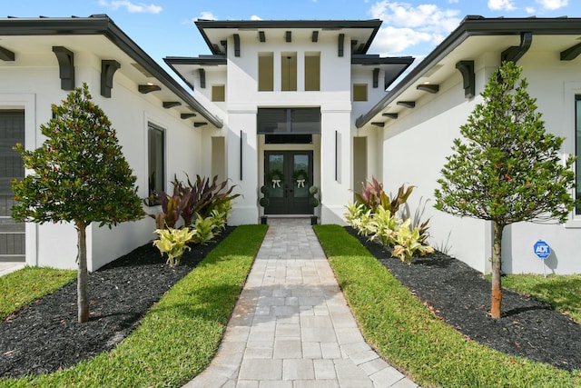 view of exterior entry with french doors and stucco siding