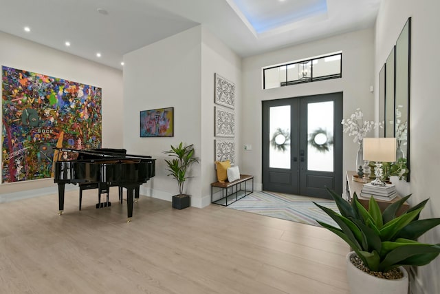 entryway featuring french doors, a towering ceiling, recessed lighting, baseboards, and wood finished floors
