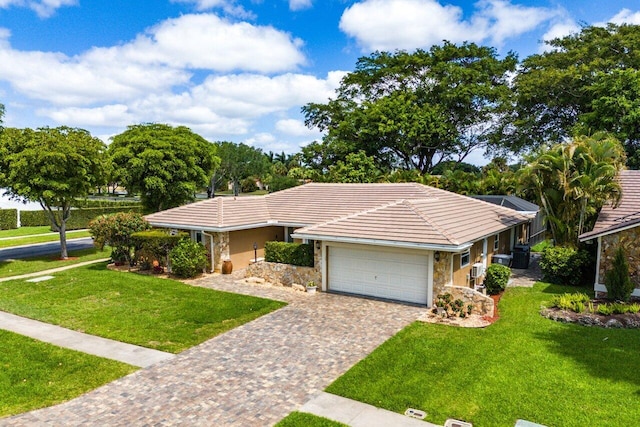 single story home featuring stone siding, an attached garage, a front yard, and decorative driveway