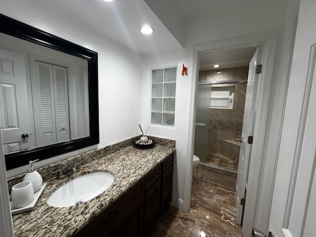 bathroom featuring marble look tiles, toilet, a shower stall, vanity, and a closet