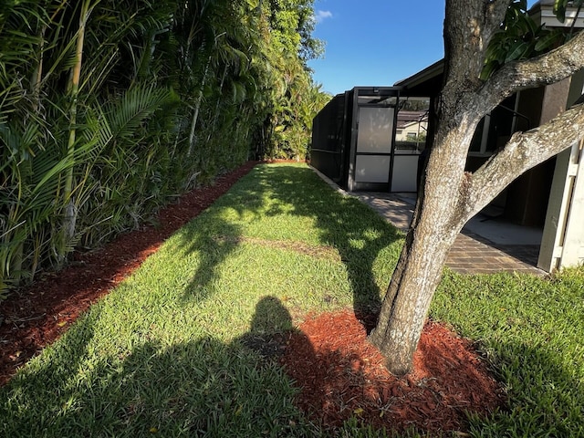 view of green lawn with a lanai