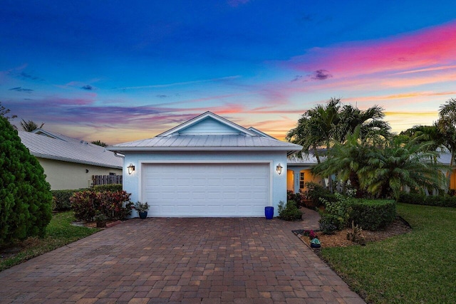 ranch-style house featuring a standing seam roof, stucco siding, decorative driveway, metal roof, and a garage