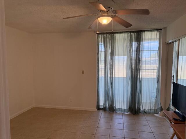 9081 Sunrise Lakes Blvd Unit 112, Sunrise, FL 33322 - empty room featuring light tile patterned flooring, a textured ceiling, ceiling fan, and baseboards