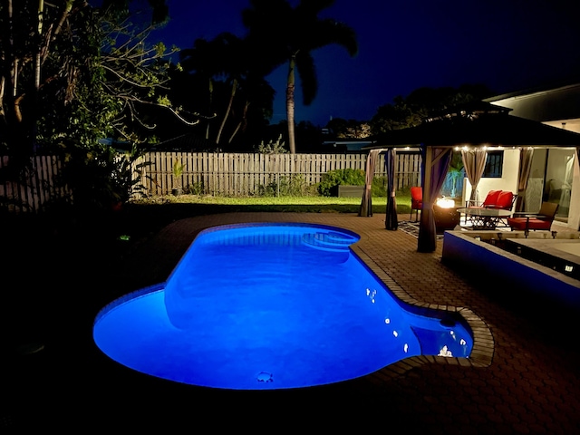 2211 NE 34th Ct, Lighthouse Point, FL 33064 - pool at twilight featuring a patio, a fenced backyard, and a fenced in pool