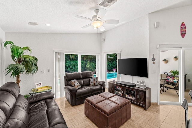 living area featuring visible vents, lofted ceiling, ceiling fan, and a textured ceiling