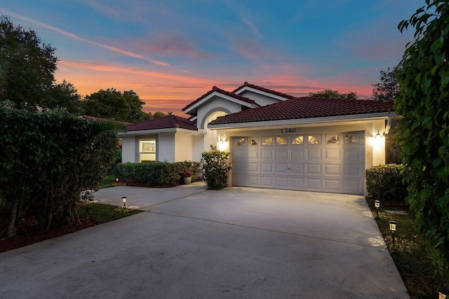 view of front facade with stucco siding, an attached garage, a tiled roof, and concrete driveway
