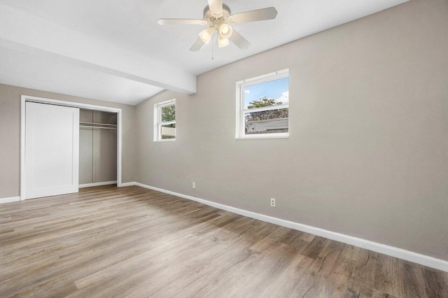 unfurnished bedroom featuring baseboards, vaulted ceiling with beams, a closet, and light wood finished floors