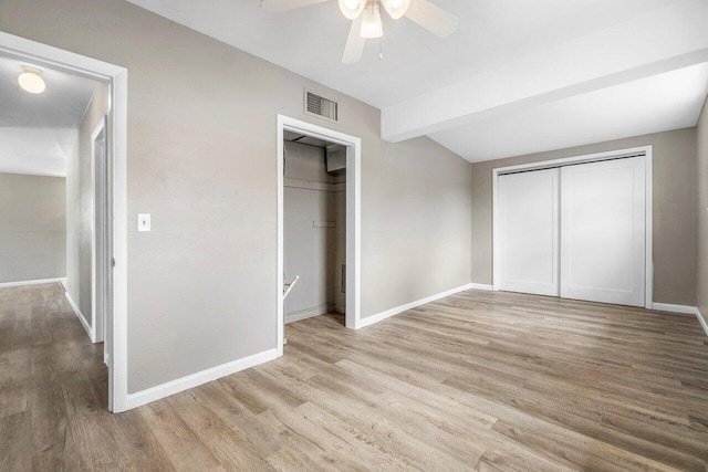 unfurnished bedroom featuring light wood-type flooring, lofted ceiling with beams, baseboards, ceiling fan, and visible vents