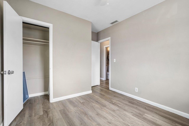 unfurnished bedroom with baseboards, visible vents, a closet, and wood finished floors
