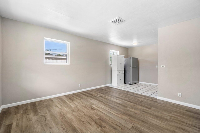 unfurnished room featuring baseboards, visible vents, and light wood-style floors