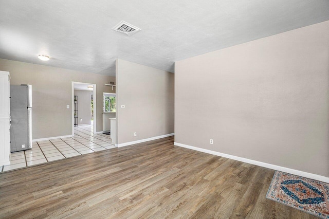 unfurnished room with baseboards, visible vents, and wood finished floors