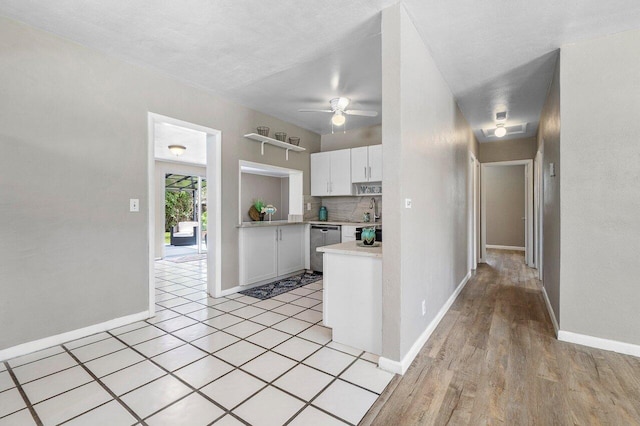 kitchen with light countertops, a ceiling fan, stainless steel dishwasher, white cabinets, and decorative backsplash
